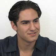 Smirking young man with short, dark, wavy hair